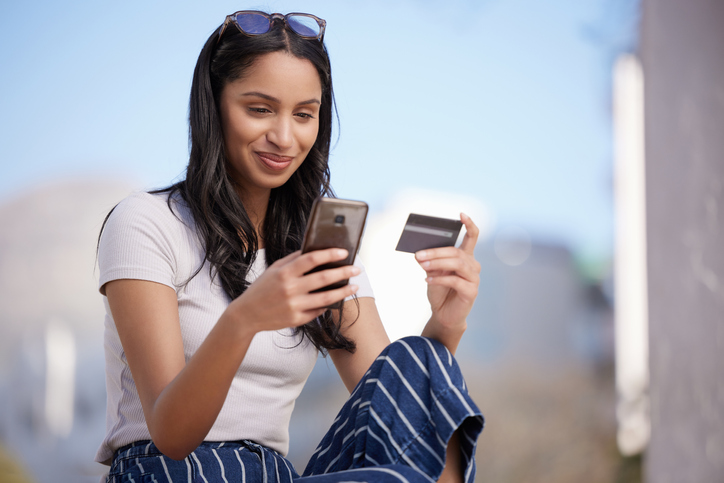 Woman smiling at credit card and phone