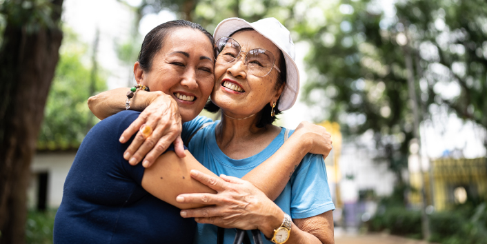 Adult daughter hugging her elderly mother, smiling.