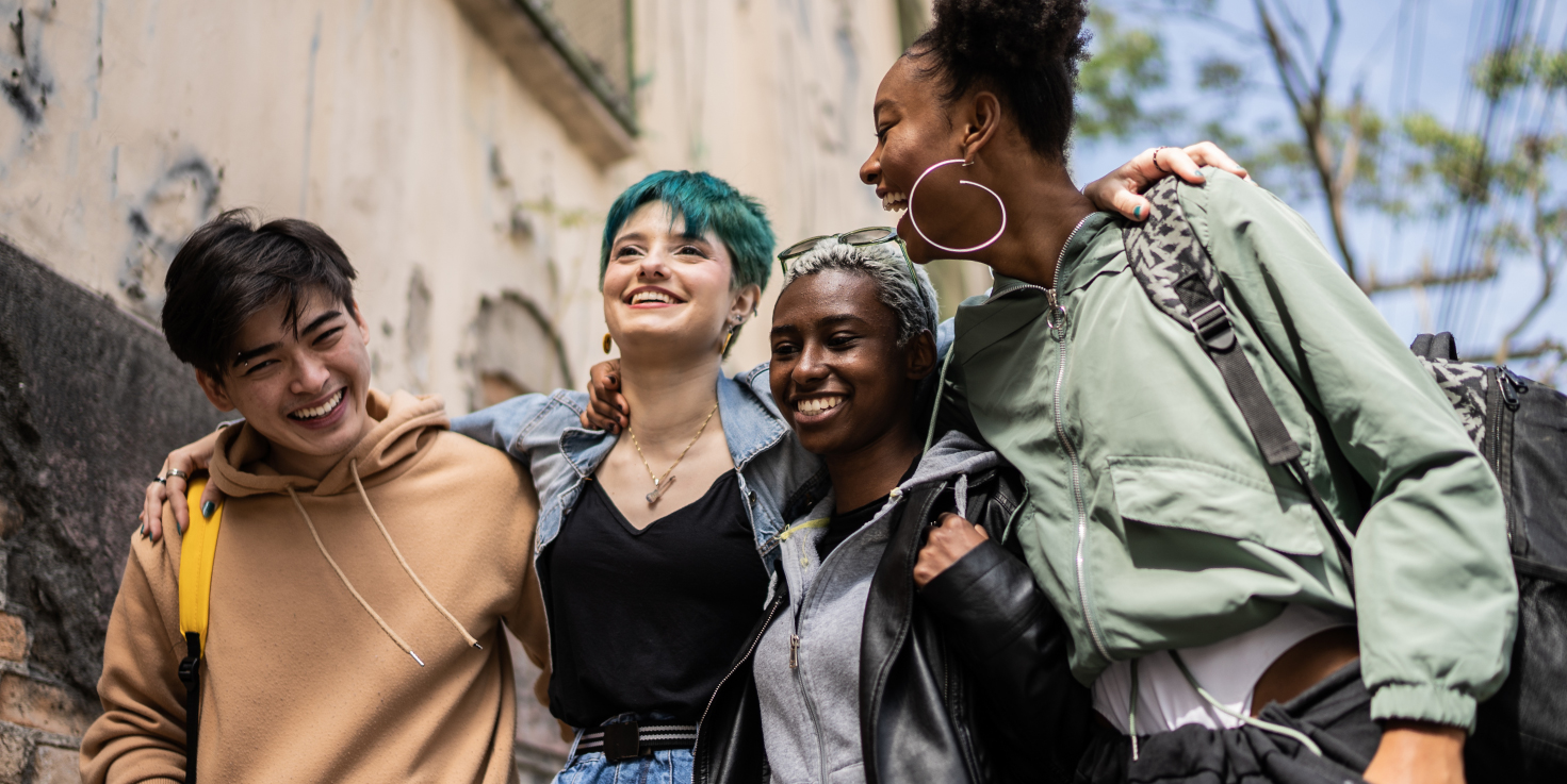 Group of friends walking and smiling with their arms around each other.